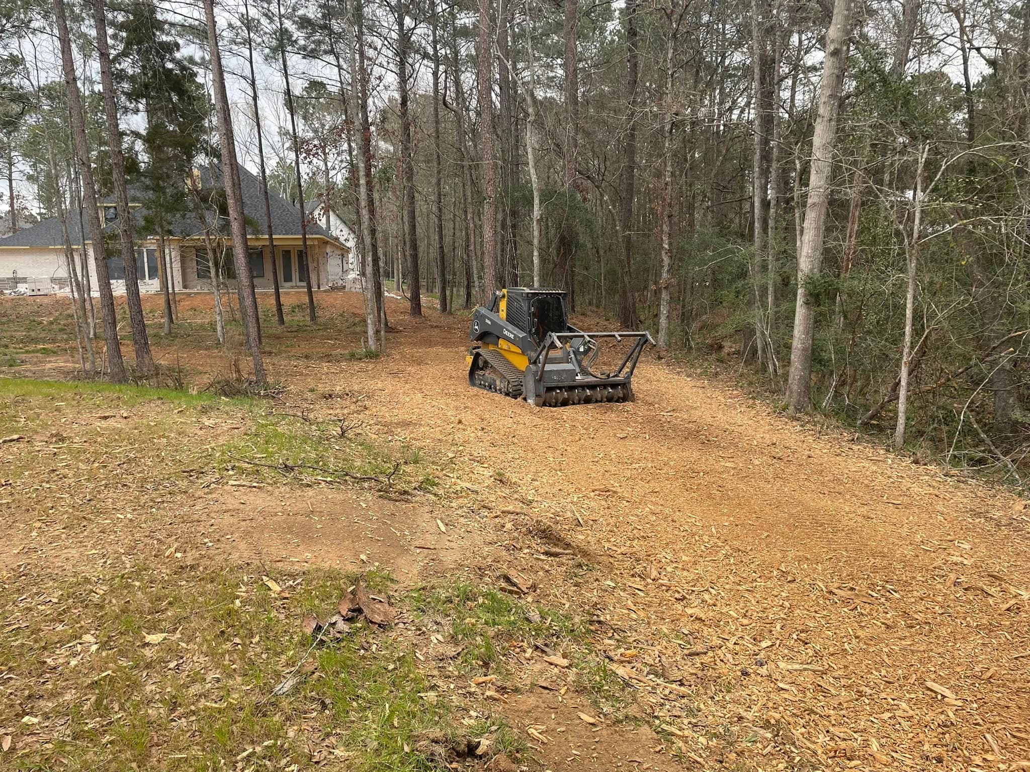 Tracked mulcher clearing a driveway path through wooded property during site prep in Tomball, TX (Harris County)